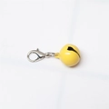 Close-up of a small yellow painted metal bell with a silver lobster clasp on white background - Painted Yellow