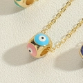 Macro shot of gold-plated evil eye cylinder pendant with colorful enamel details - Colorful