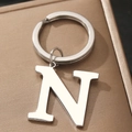 Polished silver metal letter N keychain on a textured golden brown gift box surface - Letter N