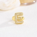 Dettaglio anello dorato con lettera E e pavé di zirconi brillanti stile palloncino - Lettera E