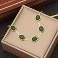 Collana a catena piatta dorata con cinque smeraldi ovali su scatola portagioie beige - Collana