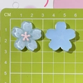 Close-up of blue resin cherry blossom charms with 2-3cm measurement on cutting mat - Light Blue