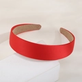 Elegant red satin wide headband with silk texture and non-slip lining on stone prop - Red