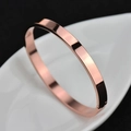 Polished rose gold stainless steel bangle bracelet on a white ceramic leaf dish - Circumference 16.5cm / 6MM Rose Gold