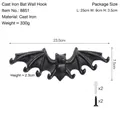 Vintage black cast iron bat wall hook with mounting screws and dimension markings - Black