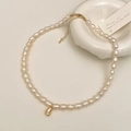 Vista macro della collana di perle d'acqua dolce con un ciondolo dorato a forma di chicco - Pendente a Fagiolo