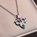Primo piano del ciondolo a cuore arcobaleno su catena in una scatola regalo beige - Collana / Arcobaleno