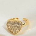 Makroaufnahme von Herzring in Gold mit Zirkonia-Besatz auf weißem Seidenhintergrund - Herzform