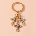 Dettaglio di un portachiavi dorato con tre ciondoli a croce ricoperti di strass brillanti - Oro