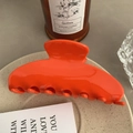 Detail of a glossy orange acetate hair claw clip displayed on a beige ceramic plate - 10cm / Orange