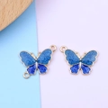 Dettaglio di ciondoli a farfalla blu con bordi dorati e finitura glitter scintillante - Anello Singolo / Blu & Blu