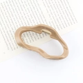 Irregular khaki acrylic hair claw clip with unique twisted ring design on a book - Khaki