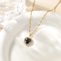 Macro shot of heart-shaped black stone pendant with pavé cubic zirconia on gold chain - September - Black