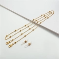 Detail of golden beaded eyeglass chain with lobster clasps and white silicone loops - Gold