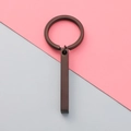 Detailed close-up of matte bronze rectangular bar keychain on a dual-tone background - Black (MP424)
