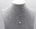 Collana a catena dorata minimalista con un singolo ciondolo di perla bianca su un busto - Oro