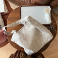 Detail einer cremefarbenen Plissee-Schultertasche auf dunklem Holztisch mit Accessoires - Naturleinen Geknitterte Textur (Naturleinen Paisley)
