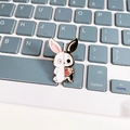 Detail of a rabbit enamel pin with a split black and white skeleton design on a keyboard - Black and White Rabbit