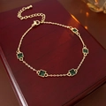Detailed shot of gold plated bracelet featuring five square emerald green stones on wood - Gold Chain / Green Square Zircon