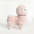 Simpatico alpaca di peluche rosa con collare in pelle marrone su fondo bianco - Rosa