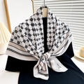 Detail of black and white geometric silk scarf tied elegantly as a chic fashion accessory - White