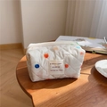 Detailed close-up of a quilted cotton makeup bag with colorful polka dots on a wood table - Colorful Polka Dots