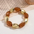 Detailed shot of amber resin beads and irregular gold beads on an elastic bracelet - Dark Coffee