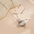 Collar con colgante de corazón plateado texturizado y circonitas en fondo crema - Estilo de Corazón con Rayas Verticales Plateadas