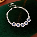Détail du bracelet fleurs argenté avec zircons bleus sur fond élégant en velours vert foncé - Argent-Bleu