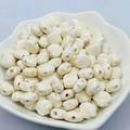 Macro shot of cream shell-shaped ceramic beads for DIY jewelry making in a white bowl - 12mm / Off-white