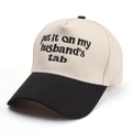 Dettaglio del ricamo 'put it on my husband's tab' su un cappellino a contrasto - Nero