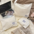 Detailed view of three white waterproof travel organizers with yellow zippers on plush rug - Milk White