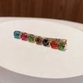 Dettaglio macro di strass colorati incastonati su un fermaglio per capelli dorato - Rotondo / Tondo Colore Misto C