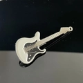 Dettaglio di un fermaglio per capelli a forma di chitarra con finitura in smalto bianco e nero - Bianco