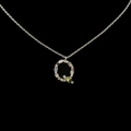 Silver letter Q necklace with colorful stones and a green pear gem on a black background - Letter Q / Silver