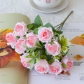 Detailed view of pink silk roses with green leaves placed on a magazine for home decor - Pink