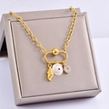 Close-up of golden necklace with shell, snail, and teardrop gemstone charms on jewelry box - Conch Shell Style