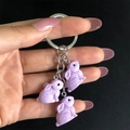 Vista dettagliata di tre ciondoli a forma di coniglio in resina lavanda su un anello d'argento - Viola