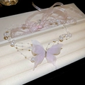 Dettaglio del ciondolo a farfalla rosa con perle e nastro in una scatola di velluto beige - Collana Di Nastro / Farfalla Rosa