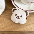 Vue détaillée d'une barrette à cheveux ours en peluche beige sur une surface en bois - Pinces cheveux bec de canard / Blanc Cassé