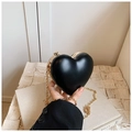 Detalle de un mini bolso de corazón negro con marco metálico dorado y cadena fina - Negro