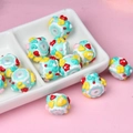Macro detail of DIY light blue acrylic beads with dessert patterns in a ceramic dish - Green Cream + Yellow Carrot + Green Bow