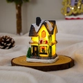Detailed view of an illuminated resin Christmas village house with snow and glowing windows - Style I
