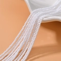 Macro detail of 2mm faceted white crystal beads cascading from a ceramic bowl for DIY jewelry - Porcelain White