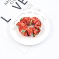 Dettaglio di scrunchie natalizio rosso con motivi festivi su un piatto decorativo - Regali di Natale Rossi