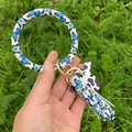 Détail du pompon à motif papillon bleu et étiquette vache sur porte-clés en cuir - Papillon Bleu
