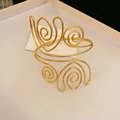 Detail van de vergulde brede holle geplooide manchetarmband met spiraalvormig ontwerp - Gouden Spiraal Stijl