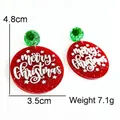 Macro shot of red glitter acrylic Christmas earrings with white Merry Christmas lettering - Red Merry Christmas Round