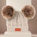 Bonnet en tricot beige pour enfants avec deux pompons en fausse fourrure et patch cuir - Blanc Cassé