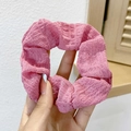 Detailed view of pink pleated scrunchie with soft elastic texture held in hand - Pink